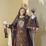 E' rappresentata su un piedistallo raffigurante una nuvola, avvolta in abiti bruni con decorazioni in oro finemente ricamate, mantello bianco e una grande corona d�oro sul capo, nell�atto di mostrare lo scapolare carmelitano. Ha in braccio il Bambino Ges�, vestito come la madre